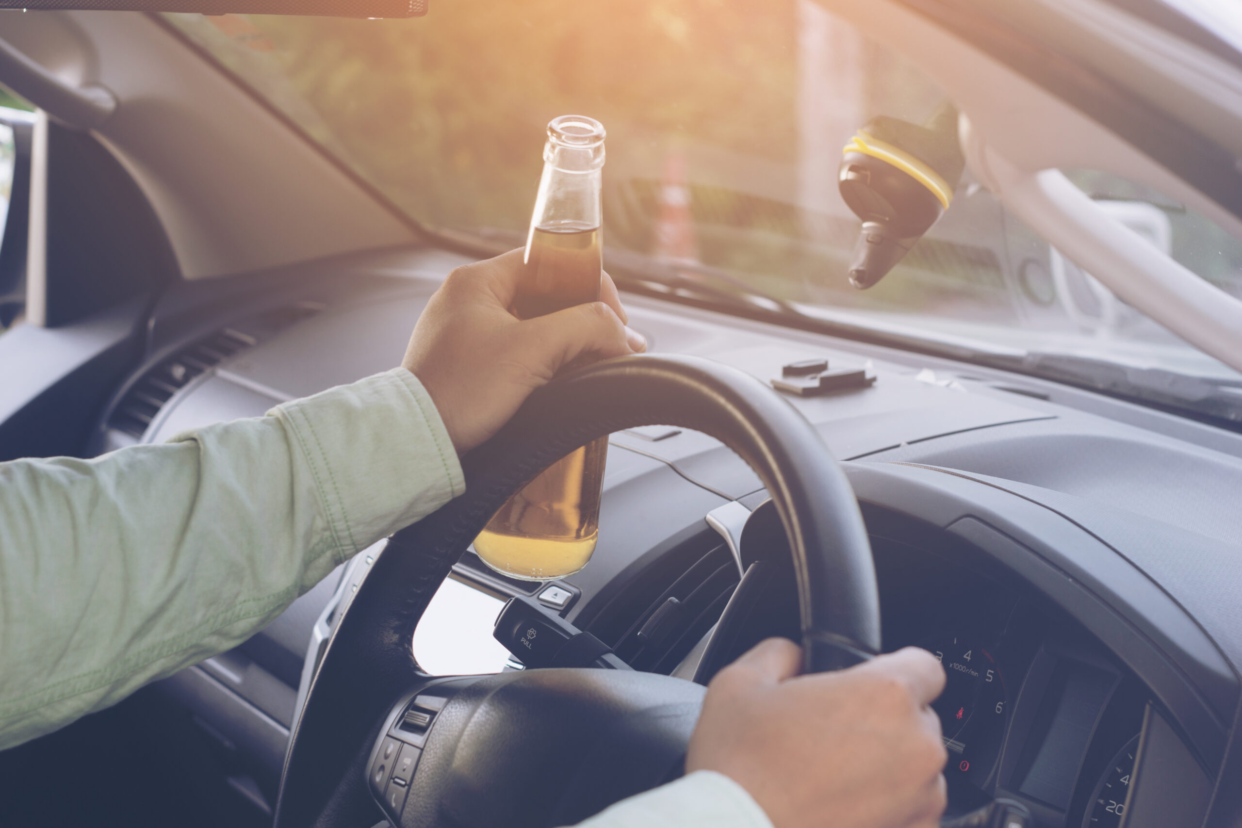 Drunk young man drives a car with a bottle of beer. This is a campaign picture of "Don't Drink for Drive.".selectove focus