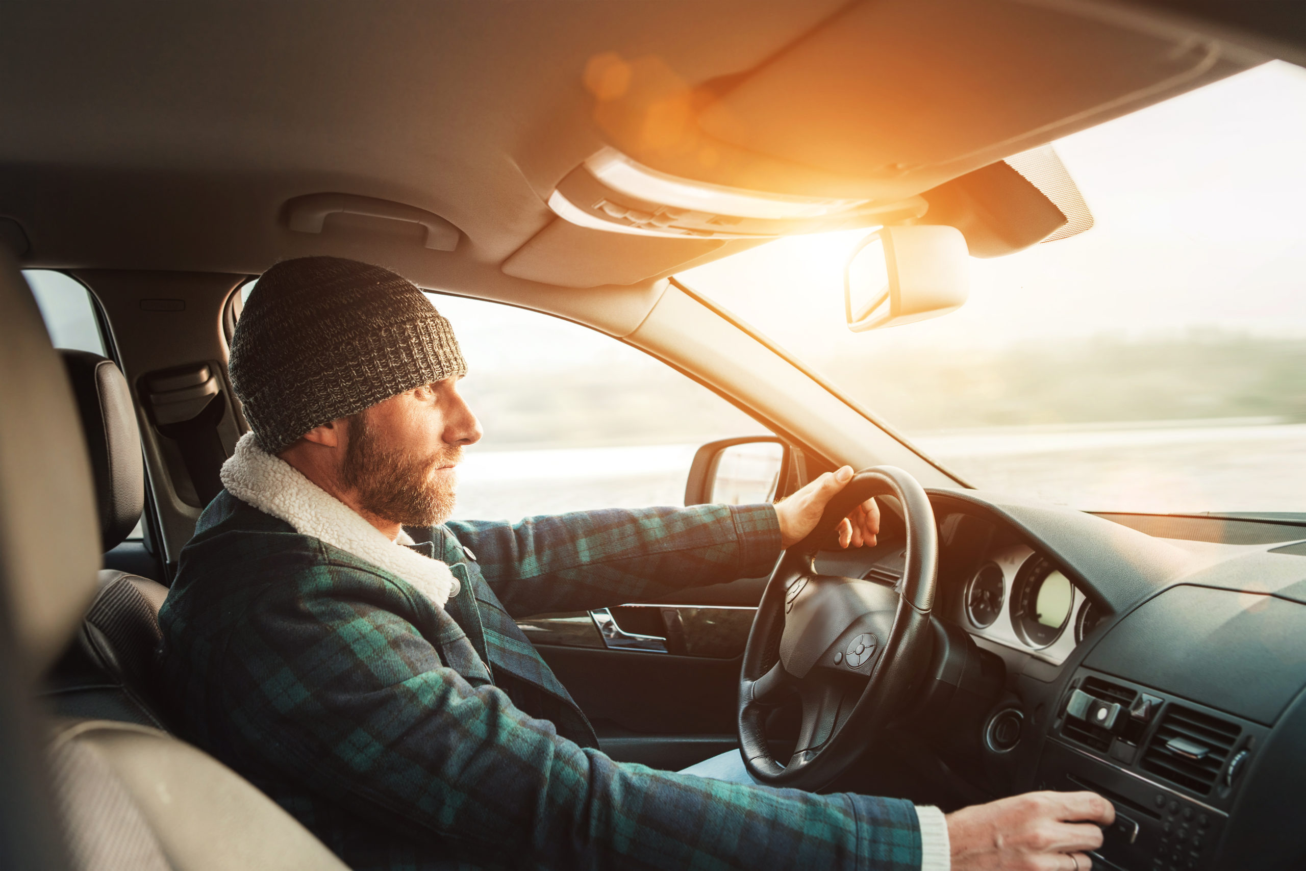 Inside car view of warm dressed Bearded Man driving a new moder