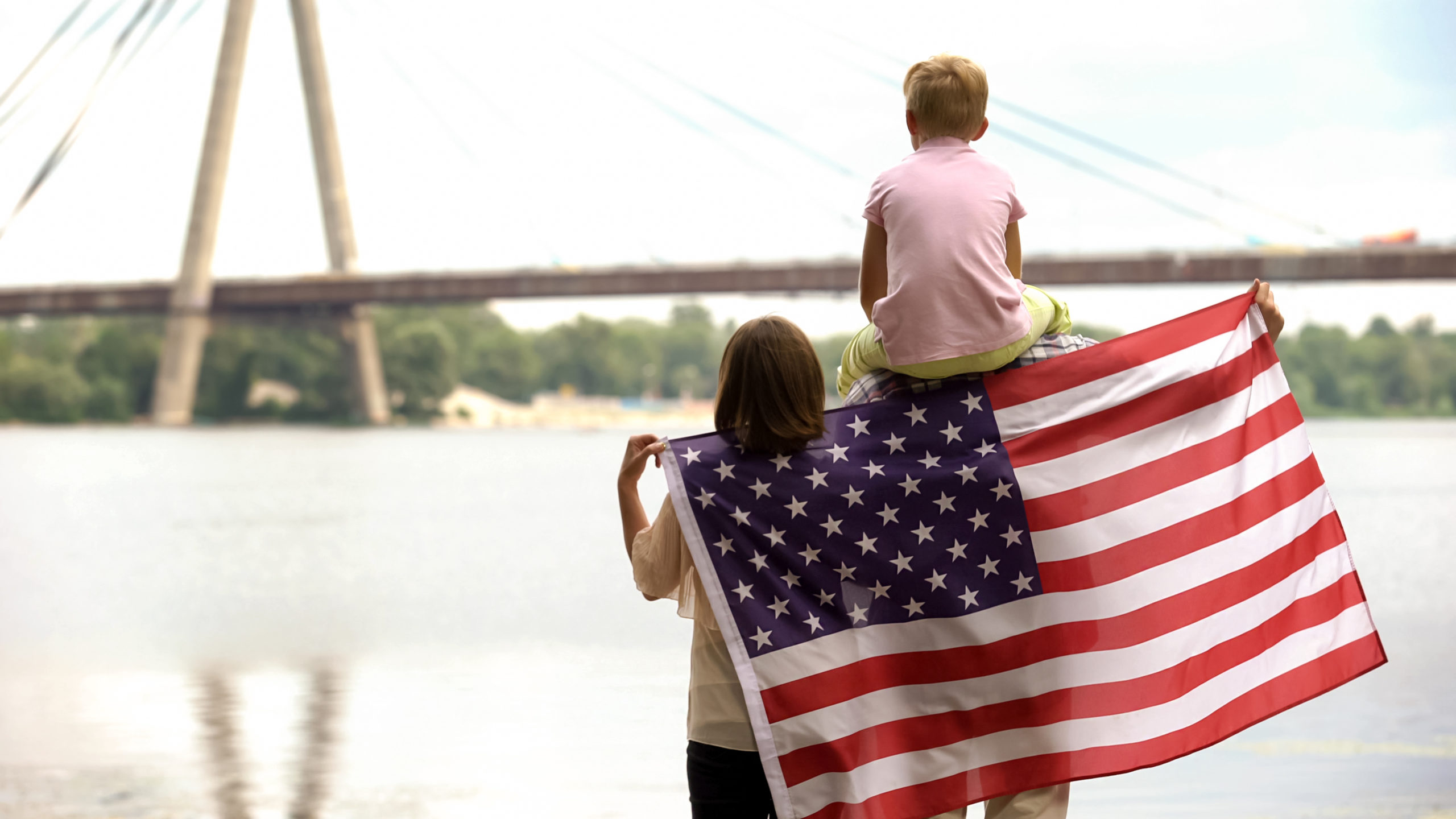 Family wrapped in American flag looking at bridge, immigration f