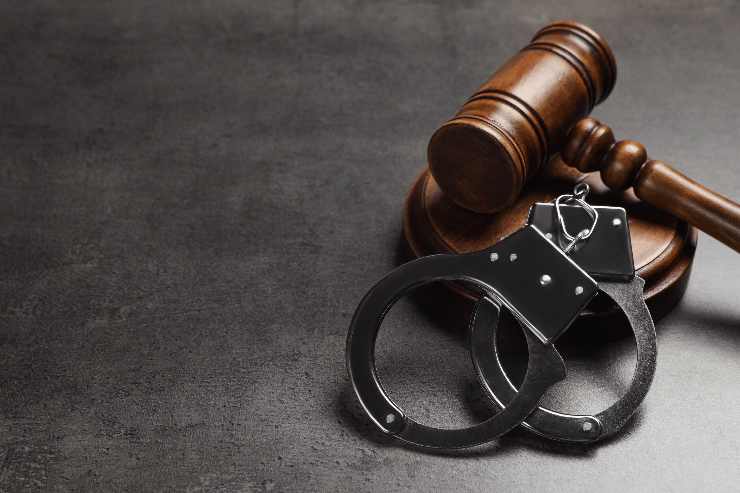 Judge's gavel and handcuffs on grey background, space for text.