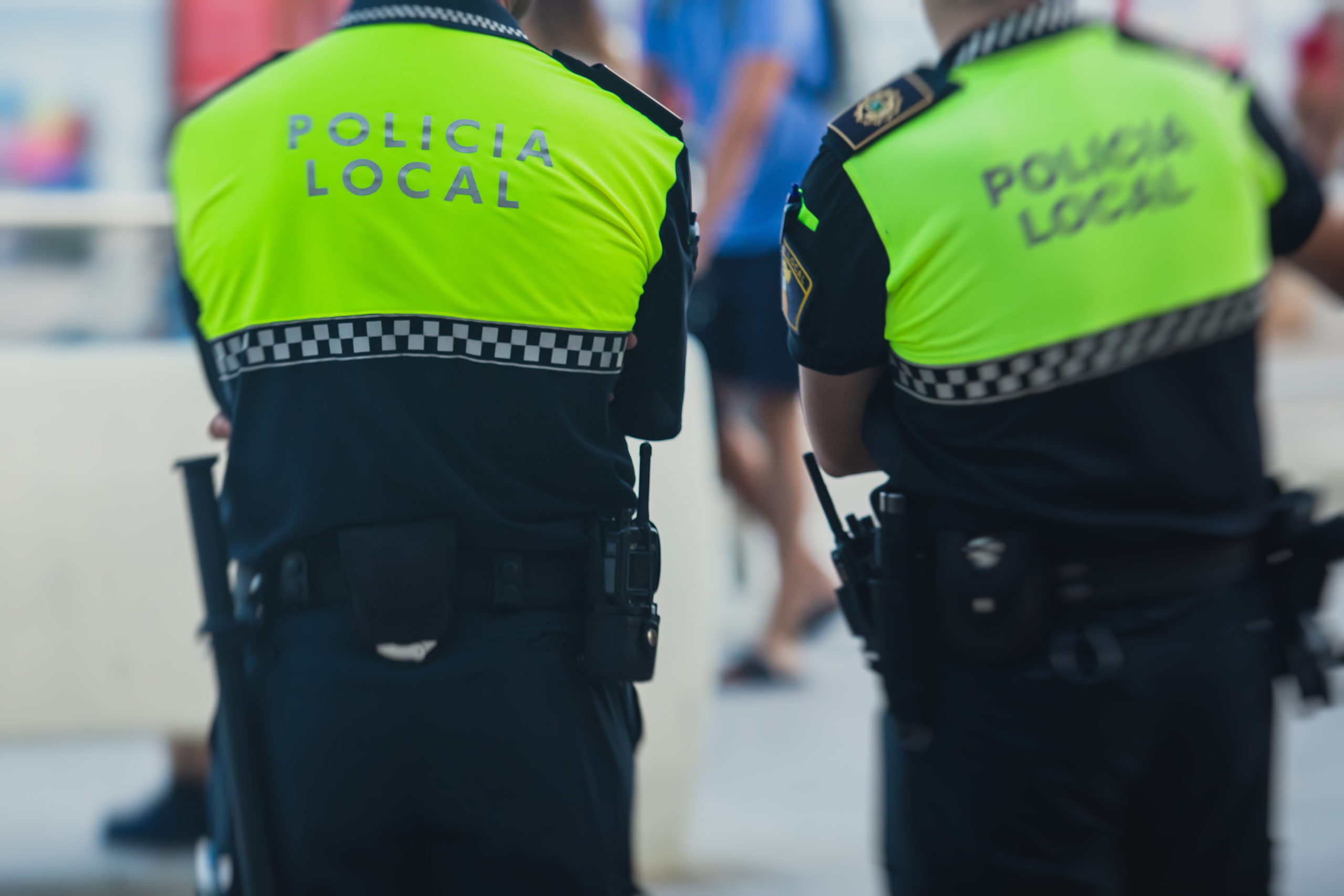 Spanish police squad formation back view with "Local Police" logo emblem on uniform maintain public order in the streets of Alicante, Spain