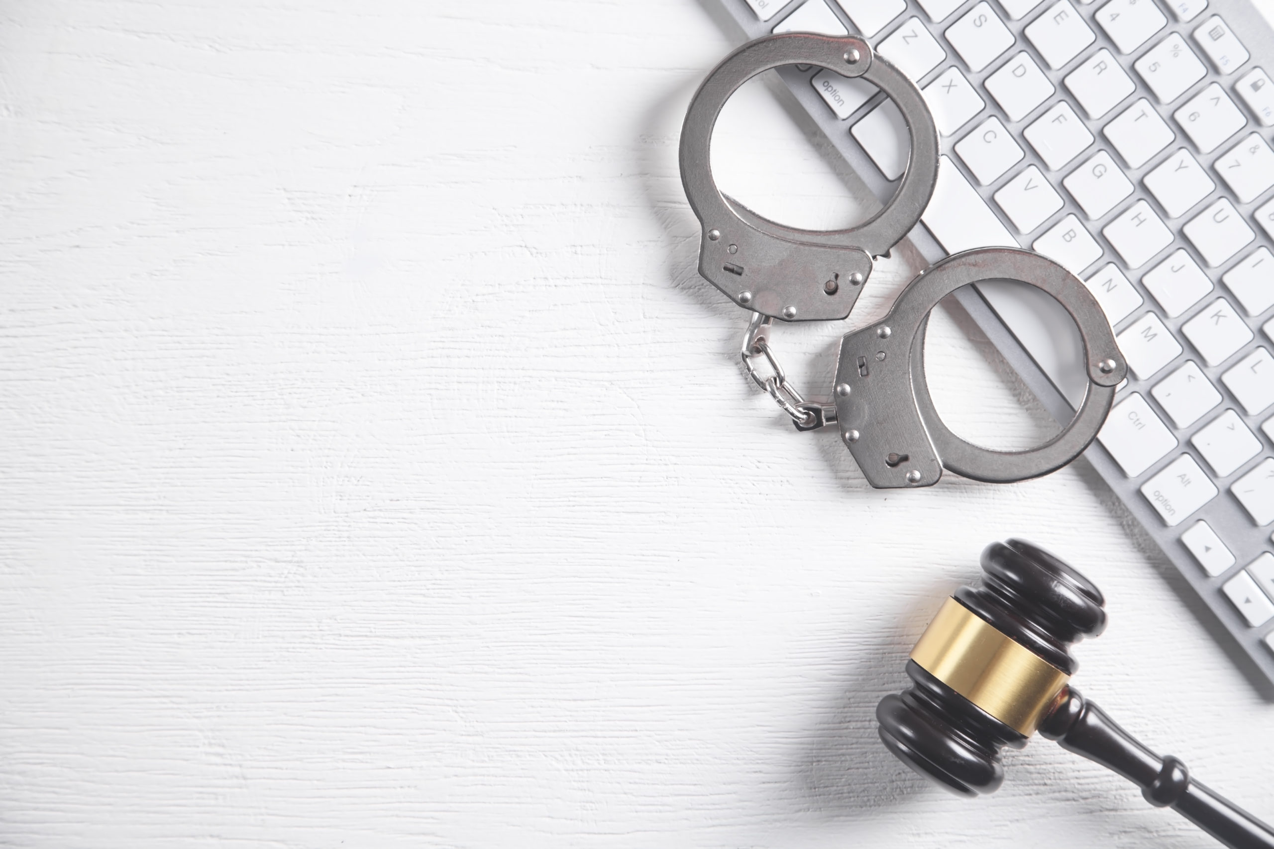 Judge gavel, handcuffs, computer keyboard.
